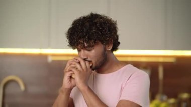 Fast food teslimatı kavramı. Neşeli adam elinde büyük bir hamburger tutuyor ve sembol göstererek havalı zevkini onaylıyor. Genç adam büyük hamburgerler yiyor, geri bildirim yapıyor. Evde aldatma yemeği. Yüksek kalite 4k