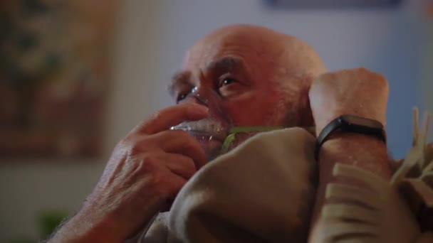 一位年老体弱的男子在家中独立治疗 戴上氧气面罩以舒缓呼吸 吸入和呼气 并把格子花包在肩上保暖 一个生病的人患有大肠病毒或 — 图库视频影像
