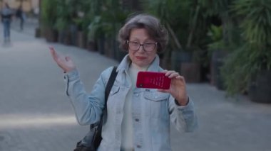 Olumlu bir yetişkin büyükanne, gezgin blogcu Avrupa 'daki aboneler için anılarını kaydediyor. Gülümseyen emekli dışarıda yaşayan torunlarına bir video hazırlıyor. Yaşlı turist kadının videosu var.