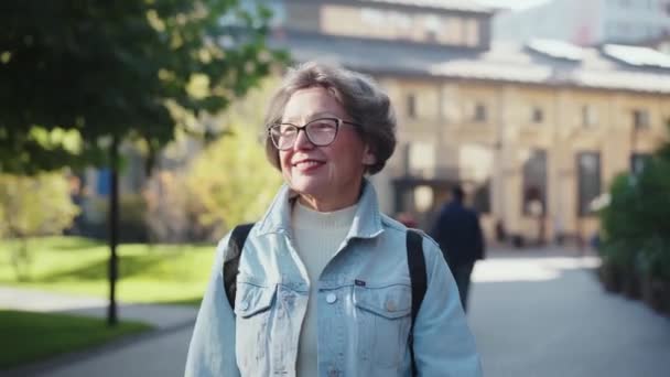 外のヨーロッパの都市地区で一人で遠足する高齢女性 祖母の散歩は 海外の孫たちを訪ねる未知の町にやってきました 都市を散策する灰色の髪の女性年金旅行者 — ストック動画