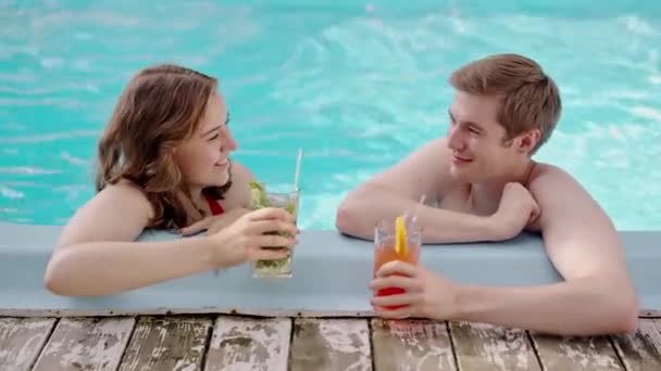 プールで会話をする若い恋人のカップル 青い水の中のリゾートで折り畳まれた手を話す2人の親友 リラックスしたハネムーンの雰囲気の中で家族の会話 高品質4Kについて — ストック動画