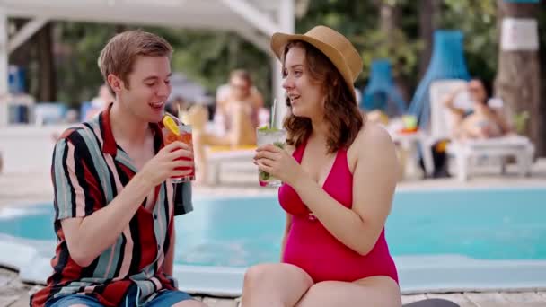 プールパーティーで満足している人々は プールサイドで新鮮なカクテルを飲みます 若いボーイフレンドとガールフレンドは 日光浴をしたり 水の近くにアペロールを飲んだりします オープンプール付きのアルコールパブ — ストック動画