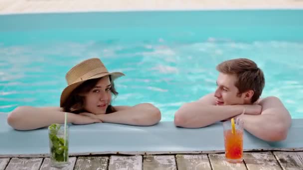 一对年轻夫妇在游泳池里聊天 在蓝色的水面上游泳时 男人和女人在中间说话 男朋友告诉他的女朋友将来的计划 高质量的4K镜头 — 图库视频影像
