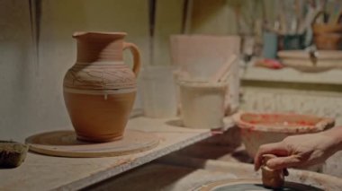 Craftsperson dönen çarkın üzerine bir parça kil koydu ve son detayları el yapımı sürahi süsledi. El işi seramik saksı. Ukrayna çömleği. Seramikçi tarafından yapılmış dekoratif kavanoz. Dokunaklı kol. Yüksek