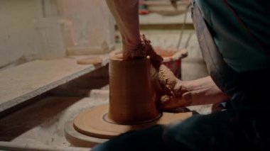 Ukrayna geleneksel seramiklerinin yaratılışı. Atölyede profesyonel timsah ustası. Adam çömlekçi çarkında çalışıyor ve kil tenceresi yapıyor. Üzerinde dönen seramik sürahiyi şekillendiren eller