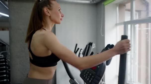 우수한 모양의 여자는 체육관에 들어가 기계의 작동을 사용자 합니다 페달링 — 비디오