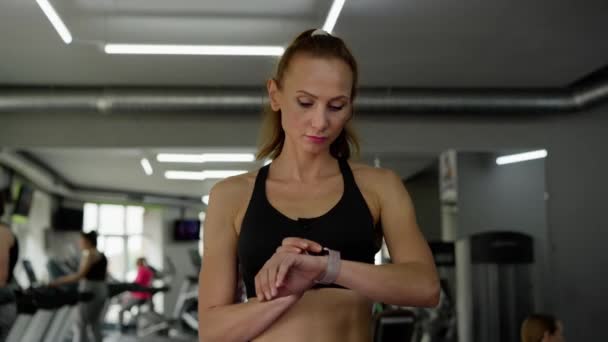 체육관에서 선수는 훈련을 준비하고 있습니다 여성은 활동의 맥박과 강도를 확인하기 — 비디오