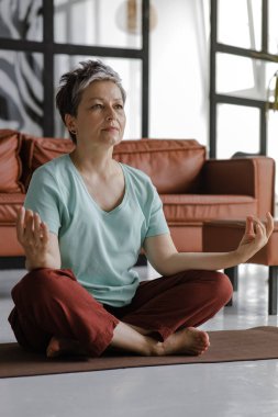 Orta yaşlı bir bayan evde yoga yapıyor. Kapalı gözlü bir kadın nilüfer pozisyonundaki bir paspasın üzerinde yan yatar. Fiziksel olarak ruhsal gelişim kavramı