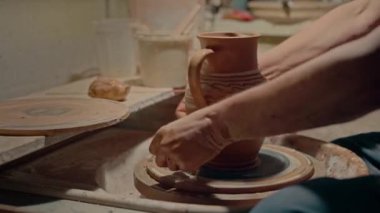 Çömlekçi ellerinin kilden yapılmış sürahisini yakından çek. Zanaatkar, kil kaseyi dönen tekerlekten keser. Çömlekçi mükemmel el yapımı sanat eserini bitiriyor. Profesyonel heykeltıraş alt seramik kaseyi kesiyor.