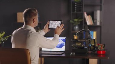 Grafik tasarımcı bir adam masanın yanına oturur, tablet kullanarak insan kafatası ve dişlerinin 3 boyutlu modelini gösterir. Dijital çizimler için bir iş bilgisayarı. Organ nakli için biyobasım organları kavramı