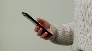 Akıllı telefonu Kafkas kadınlarının ellerinde kapat. Gri arka planda izole edilmiş cep telefonu yazan kadın eller. Cep telefonuyla. Cep telefonu görüntülerini dinleyip mesaj yolluyorlar. Cevap ver. Sadece...