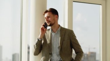 Ofiste çalışan genç bir iş adamı. Mutlu adam telefonla birileriyle konuşuyor. O mutlu. Adam, tatil planları hakkında konuşmak için karısını arıyor. Yüksek kalite 4k görüntü