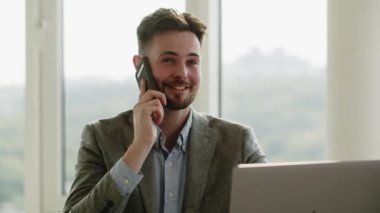 Ofiste çalışan yakışıklı bir iş adamı. Dizüstü bilgisayarda yazan odaklanmış genç bir adam. Dolly vurdu. Gün ışığı. Teknoloji. - Evet. Yüksek kalite 4k görüntü