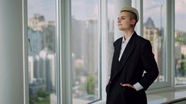 Modern Ofis 'te Kısa Beyaz Saçlı Güzel Otantik LGBT kadın portresi. Pencereden bakar ve büyük planlar ve projeler hayal eder. Arka planda büyük şehir var. Yüksek kalite 4k