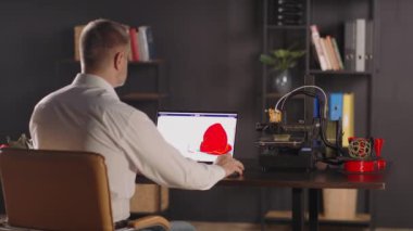 Grafik tasarımcı bir adam dizüstü bilgisayar kullanır, kırmızı renkli bir insan kalbi çizimi yapar. 3D yazıcılarda organ nakli kavramı, organ naklinin geleceği.