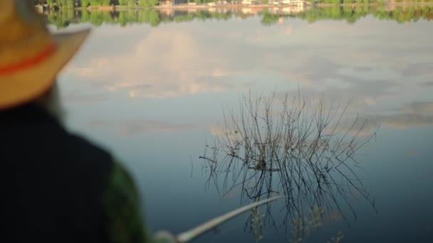 村の地元の湖で釣りをする祖父 屋外で魚を捕まえるおじいちゃん 自然環境で魚の棒を持っている上級者の背面の眺め 引退した漁師の冷静さ 高品質4Kについて — ストック動画