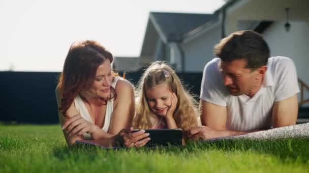 美国梦中的家庭在草坪上的房子附近放松一下 躺在紫色的毛毯 地毯或地毯上 母亲和女儿彼此相爱 妈妈和孩子亲吻和拥抱一个爸爸 — 图库视频影像