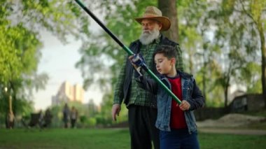 Dışarıda iki farklı nesil birlikte balık avlıyor. Torunum büyükbabayla konuşurken olta almaktan zevk alıyor. Büyükbaba torununun nasıl olta attığını izliyor. Yüksek kalite 4k görüntü