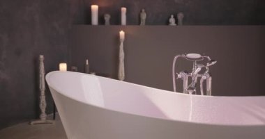 Video, ana odak noktası olarak serbest küvet bulunan modern bir banyo içini gösteriyor. Küvet beyaz akrilikten yapılmıştır ve parlak, çağdaş bir tasarıma sahiptir. Konumunu aldı.