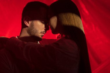 İki aşık arka planda neon ışıkta sarılır. Evde erkek arkadaşına dokunan bir kadın. Sanat aşkı tutkusu kavramı. İlişki 4k görüntülerinde ön sevişme