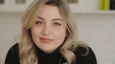 Çekici sarışın genç bir kız. Çekici bir bakışla ve yanaklarında gamzeleri olan. Göz kırpıyor, gülümsüyor ve kameraya bakıyor. Parlak bir derginin kapağı için pozlar veren güzel bir bayan model.