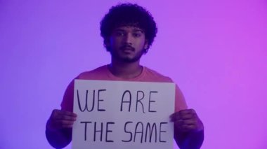 Afro-Amerikalı bir aktivist kendine güvenen bir bakış açısıyla ışıldayan renkli ışığın arka planında ayrımcılığa karşı slogan taşıyan bir poster sergiliyor. Birlik ve eşitlik kavramı