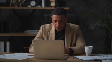 Takım elbiseli siyah bir adam iyi haberi okuduktan sonra sevinmeye başlar. Kahverengi ceketli genç bir adam çeşitli belgelerin bulunduğu bir masada oturuyor ve bir dizüstü bilgisayarda çalışıyor. Yüksek kalite 4k