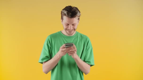 Усміхнений Хлопець Зеленій Футболці Стоїть Жовтій Стіні Телефоном Руках Молодий — стокове відео