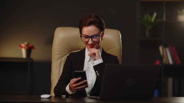 若いビジネス女性は スマートフォンサーフィンを使用するための自由な時間を持っています 勤務時間中に恋人とチャットする笑顔のビジネス女性 マネージャーの女性は働いていたときに匿名からフラットメッセージを受け取りました — ストック動画
