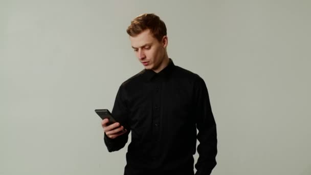 Siyah Tişörtlü Genç Akıllı Telefonu Tatmin Edici Bir Şekilde Kullanıyor — Stok video