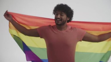 Neşeli bir gülüşü olan, neşeli ve neşeli bir Hintli adam gülüyor, LGBT seks azınlıklarının gökkuşağı bayrağını açıyor ve gösteriyor. Birliktelik ve eşitlik kavramı