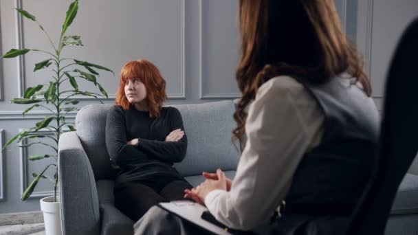 パーソナルセラピー 女性心理療法士が患者と会話する ソファーに座っている若い赤い髪の少女は 彼女と会話を開始することができますどの点から知らない — ストック動画