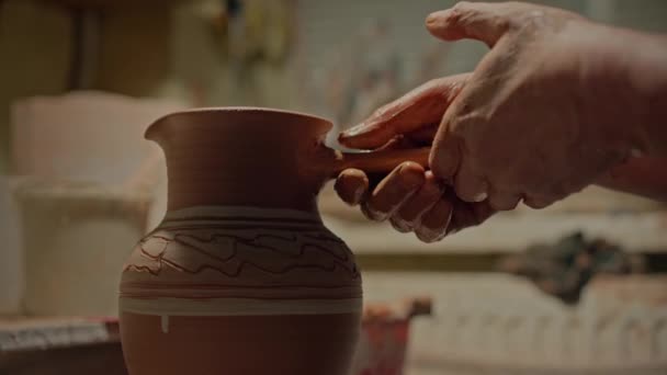 ポスターの手を閉じて ジャグを粘らせ その形を強化するハドルを攻撃します 彼の手作りのクロッカーの余分な細部と働く男性の専門の陶器 ワークショップでセラミックポットを作る古い職人 — ストック動画