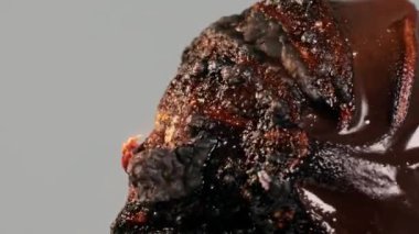 Yanan çikolatalı bir tatlı alevlerde yanar ve erir, dumanda kabarcıklar ve çıbanlar çıkarır, gri arka planda izole bir şekilde. Kapatın. Yavaş çekim modu. Yüksek kalite 4k görüntü