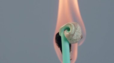 Gümüş folyoya sarılı gümüş bir pamuk çubuğa sarılı, gri bir zeminde izole edilmiş, yanıklar, erimeler, sıvılaşmalar, köpükler ateşin etkisi altında düşer. Yavaş çekim modu. Kapat