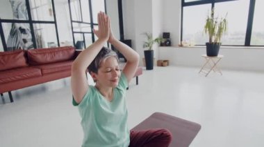 Yaşlı kadın evde yoga egzersizi yapıyor. Olgun kadınlar stüdyoda meditasyon yaparlar. Hayatındaki tüm kötü şeyleri serbest bırakmak için vücudunu ve zihnini rahatlat. Yüksek kalite 4k görüntü