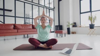 Yaşlı kadın evde yoga egzersizi yapıyor. Olgun kadınlar meditasyon yapar. Ellerini kaldırır ve gözlerini kapatır. Derin nefes al. Yüksek kalite 4k görüntü