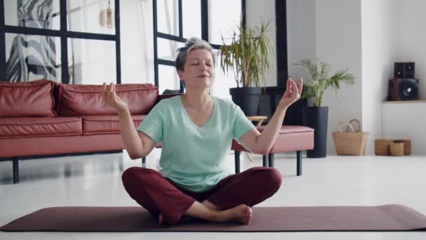 老太太在家做瑜伽运动 成熟的女人有冥想 她闭上眼睛 试图找到内心的集中 快乐的老生活 高质量的4K镜头 — 图库视频影像