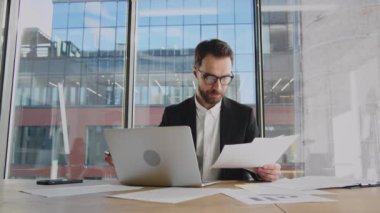 Bilgisayar ekranına bakarak online ticaret piyasasının dijital verilerini analiz eden olgunlaşmış bir işadamı. Gözlüklerini tak ve dizüstü bilgisayara bak. Yüksek kalite 4k