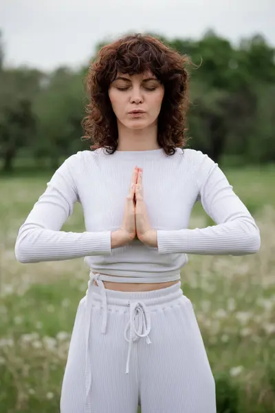 女孩以祷告的姿势冥想 运动女性缓慢地呼吸以获得脉轮平衡 女士交叉的手掌在一起放松 女性闭上眼睛 把心思集中在瑜伽上 高质量的照片 图库图片