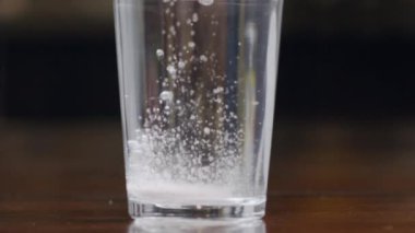 Yuvarlak, beyaz bir hap bir bardak suya düşer, çözünür ve kabarcıklar oluşturur. Aspirin, antiseptik ya da antipiretik reklamları. Güvenli ve uygun fiyatlı sağlık hizmeti kavramı. Kapat