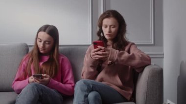 İki ciddi konsantre genç kız rahat bir atmosferde odadaki kanepede oturuyor. Kız arkadaşlar ya da kız kardeşler akıllı telefon ve internet kullanır. Bayan öğrenciler hafta sonlarını ve boş zamanlarını