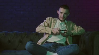 Konsol oynayan genç bir adam. Erkek siber sporu, evde oyun oynamak. Duygusal bir oyuncu. Erkek, kanepede oturuyor ve playstation 'da oyununu kaybediyor. Talihsiz oyuncular tepki verir. Yüksek kalite 4k