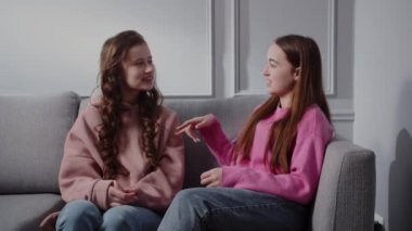 İki gülümseyen, çekici ergen kız kanepede oturup konuşuyorlar. Kız arkadaşlar ya da kız kardeşler neşeli duygularla ve rahat bir ortamda neşeli bir ruh haliyle sohbet ederler. Şey...