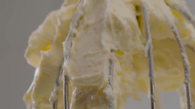 Mutfakta dönen çırpı. Profesyonel ya da amatör yemek malzemeleri. Şef eritilmiş tereyağını şeker ve yumurtayla karıştırıyor. Erimiş krema, tatlı eklemeye hazır. Yüksek kalite 4k görüntü