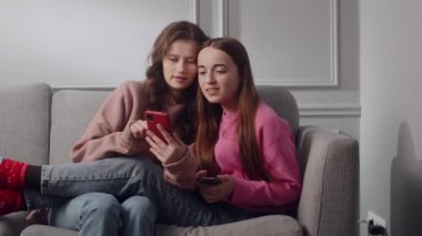 İki gülümseyen genç kız rahat bir atmosferde odadaki kanepede oturuyor. Kız arkadaşlar ya da kız kardeşler akıllı telefon ve internet kullanır, komik videolar izlerler. Bayan öğrenciler hafta sonlarını geçirir