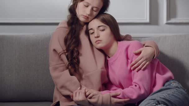 かわいい女の子 ティーンエイジャーや悲しい感情の学生はソファーに座って抱きしめ お互いを慰めます 若い女性が下を見下ろし 彼女の肩を打つ友人の胸に手を貸し 困難にサポート — ストック動画