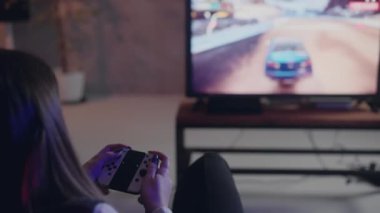Yarış arabaları video oyunu oynayan bir kadının arka çekimi. joystick kullanan ve yarış simülatörü oynamaya odaklanmış genç bir kız. Televizyon izleyip, oyun oynuyordu. Yüksek kalite 4k görüntü