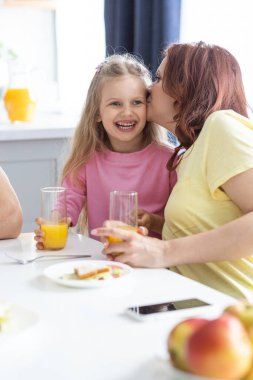 Annesi ve kızı olan arkadaş canlısı bir aile masada oturup mutfakta öğle yemeği yer. Genç bir kadın anne, gülen küçük kıza sarılıp kulağına komik bir şaka fısıldıyor. Şey...