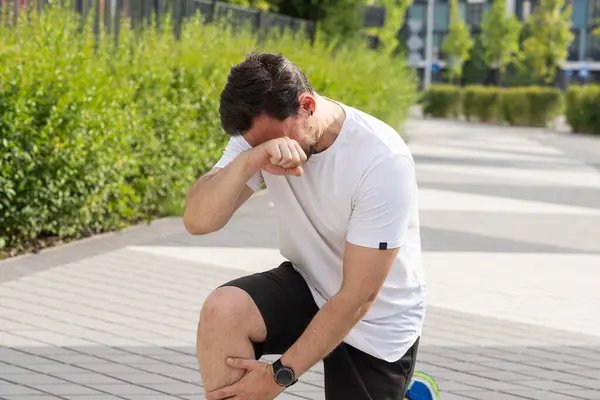 Kaldırımda genç bir adam diz çöker, bacağına dokunur ve yüzünü acıyla kaplar. Bir sporcu koşarken burkulma ya da lüksle yaralanır. Bir adam antrenmanı yarıda kestiği için üzgün.